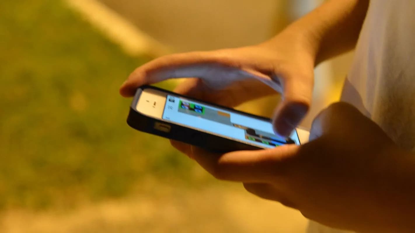 Pessoa segura um smartphone ao ar livre, representando o uso de celular alcançado pela nova regra de bloqueio de ligações não autenticadas