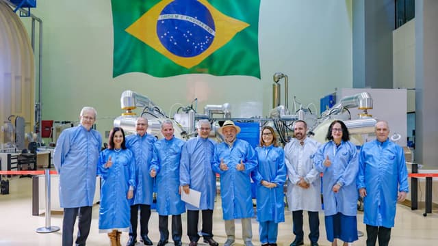 Lula posa com cientistas de jaleco em laboratório do INPE, com bandeira do Brasil ao fundo; foto de arquivo de visita a instituto de pesquisa