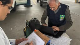 Fiscal inspeciona documentos em posto de combustível ao lado de frentista