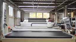 Chão de fábrica com máquina industrial de corte em operação