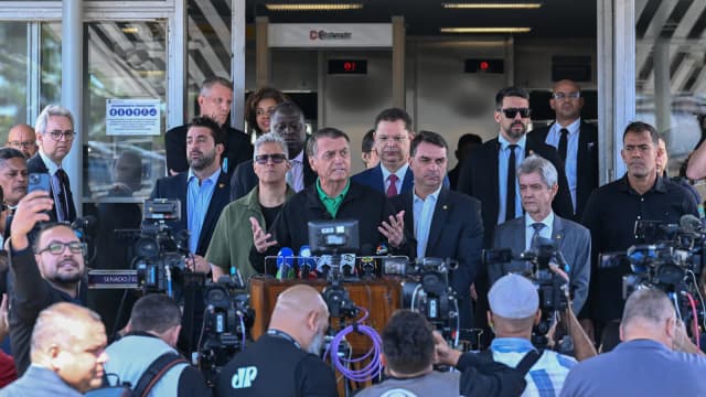 Flávio Bolsonaro ao lado do pai, Jair Bolsonaro, durante coletiva de imprensa cercada por microfones e câmeras