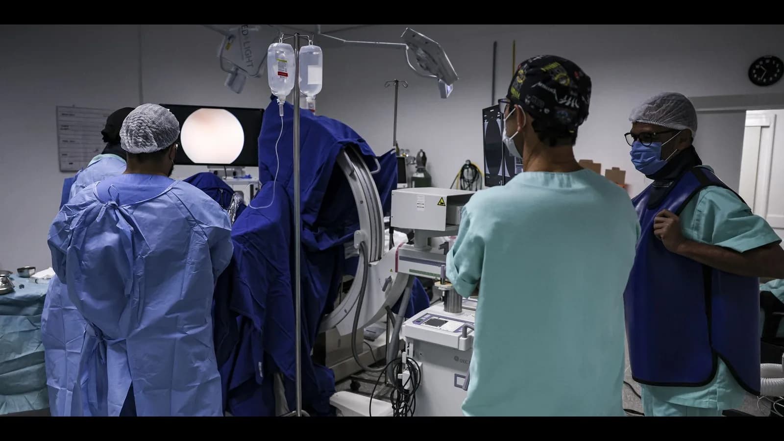 Equipe médica com jalecos e máscaras em sala de procedimento de hospital do SUS