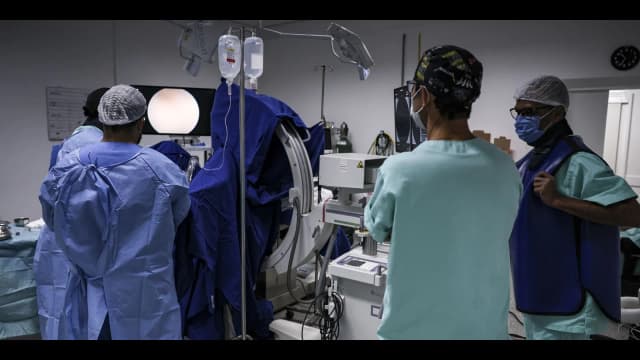 Equipe médica com jalecos e máscaras em sala de procedimento de hospital do SUS