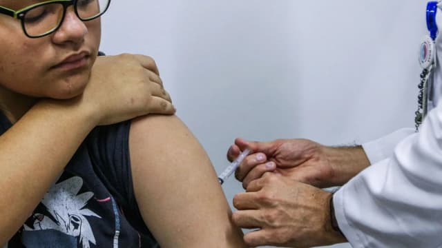 Adolescente recebe aplicação de vacina no braço em posto de saúde