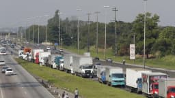 Fila de caminhões parados no acostamento de rodovia, com motoristas ao lado dos veículos (foto de arquivo)