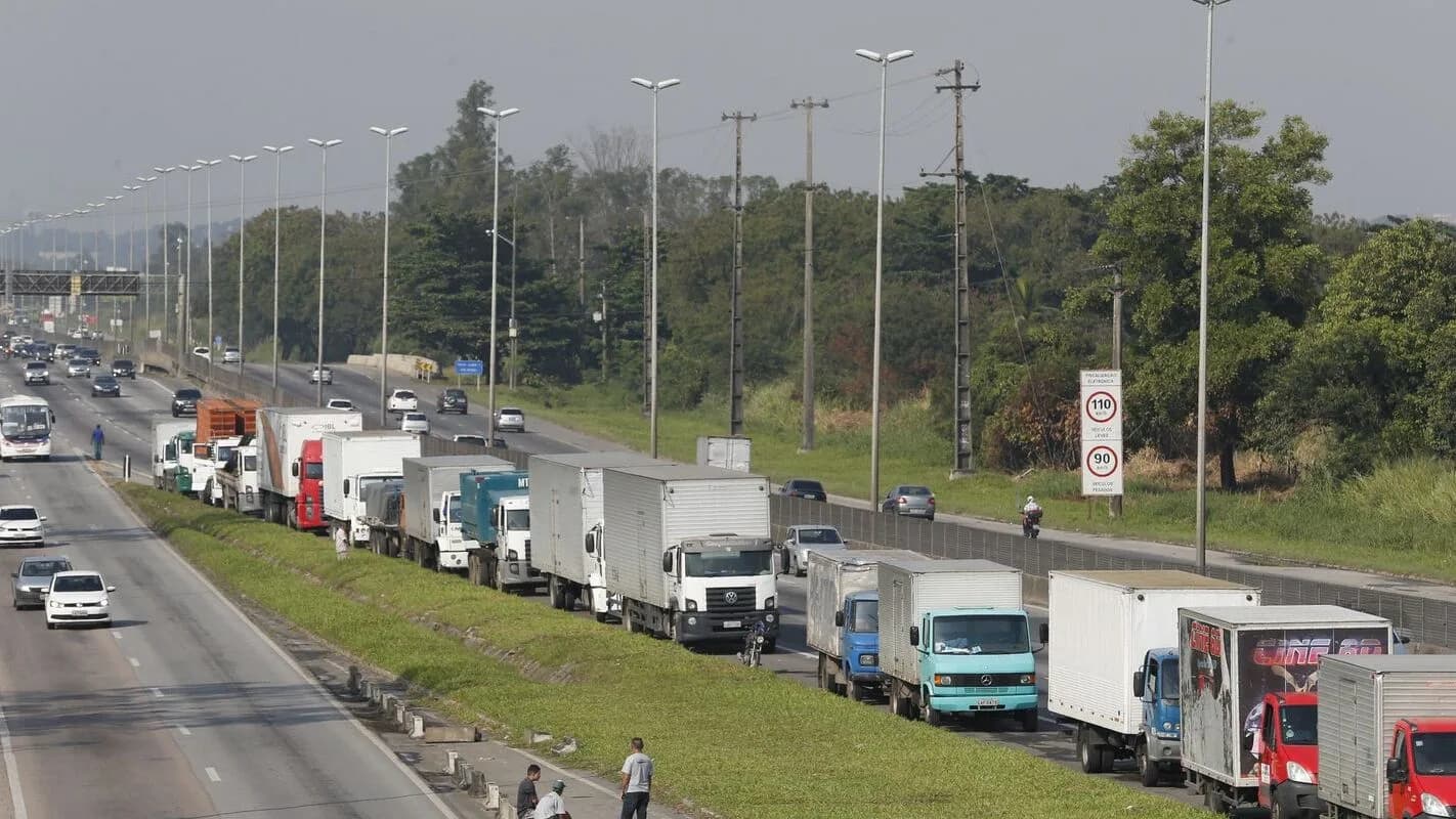 Fila de caminhões parados no acostamento de rodovia, com motoristas ao lado dos veículos (foto de arquivo)