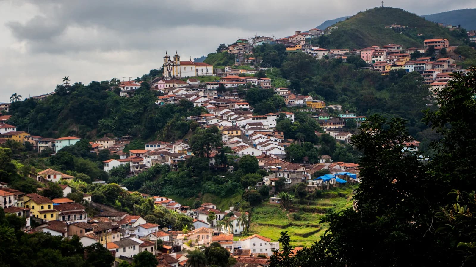 Vista panorâmica do centro histórico de Ouro Preto, com igreja no alto da colina em dia nublado
