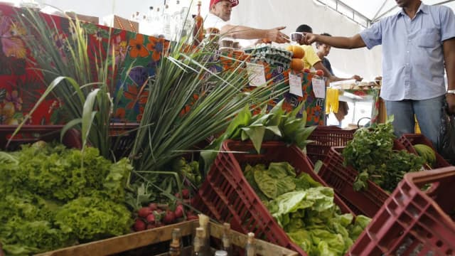 Vendedor entrega produto a cliente em feira livre