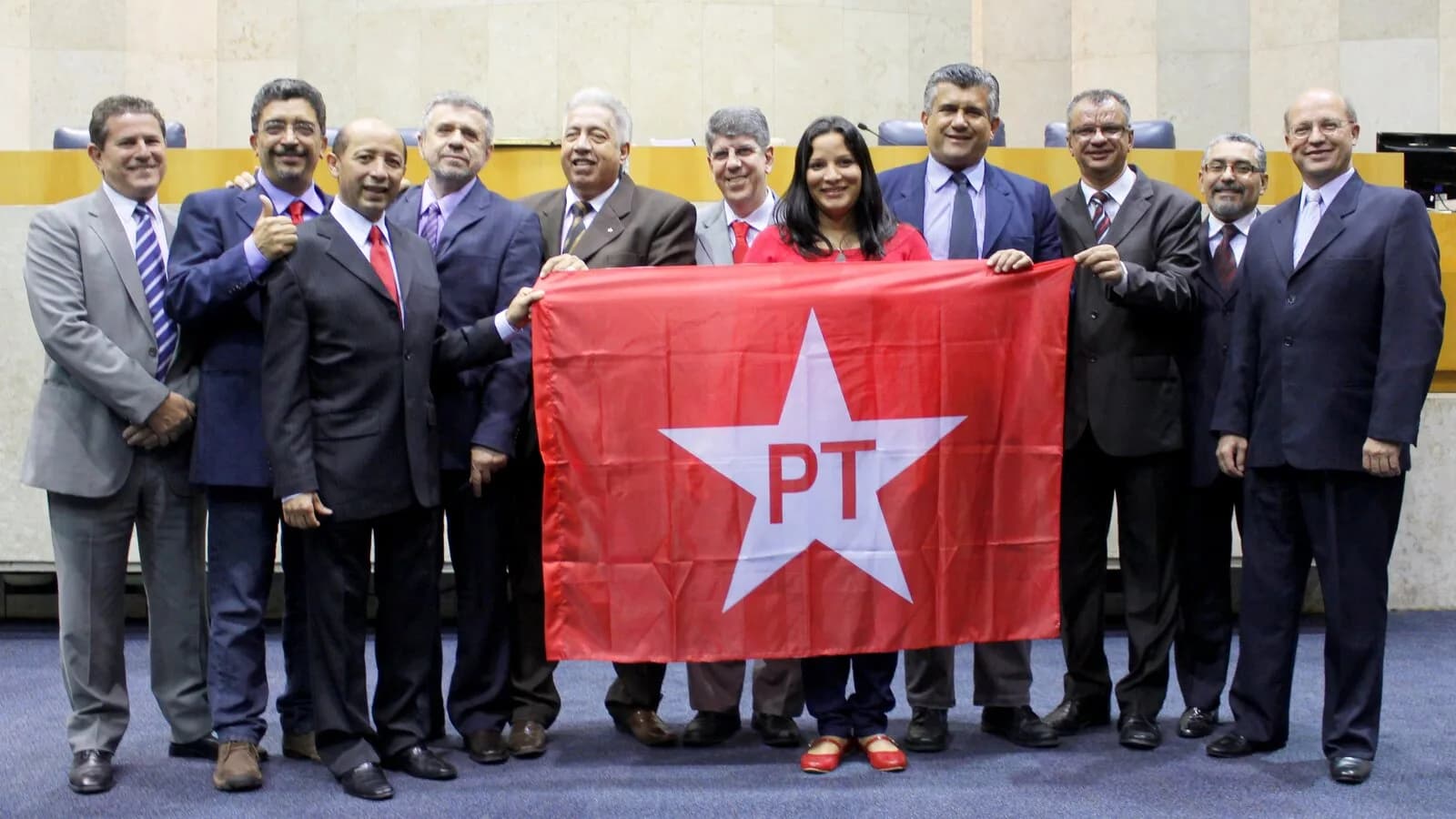 Bancada de vereadores do PT reunida no plenário da Câmara Municipal de São Paulo com bandeira do partido