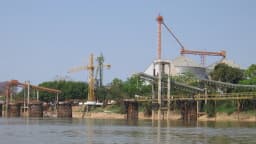 Estrutura de silos e guindastes para carregamento de grãos em terminal de exportação às margens de um rio