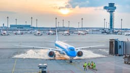 Avião Embraer E195-E2 taxia em pátio de aeroporto ao pôr do sol, cercado por outras aeronaves e equipe de solo (imagem de arquivo do modelo)