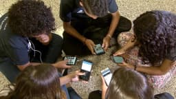 Jovens usam celulares em grupo