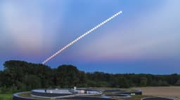 Sequência composta mostrando a Lua em eclipse subindo no céu ao anoitecer, sobre um prédio moderno