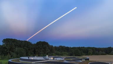 Sequência composta mostrando a Lua em eclipse subindo no céu ao anoitecer, sobre um prédio moderno