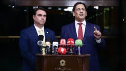 Senador Flávio Bolsonaro fala em entrevista coletiva em frente a microfones de emissoras de TV e rádio