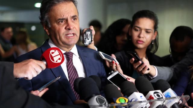 Senador Aécio Neves fala a jornalistas cercado de microfones em coletiva de imprensa