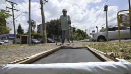 Painel de propaganda eleitoral montado em via pública, com homem ajustando a estrutura