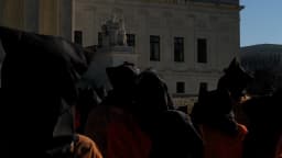 Manifestantes usam capuzes pretos e macacões laranja em ato pelo fechamento da prisão de Guantánamo em frente à Suprema Corte dos EUA