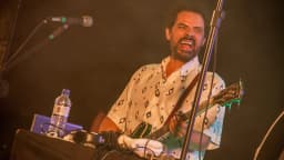 Curumin canta e toca instrumento em show ao vivo