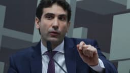 Presidente do Banco Central, Gabriel Galípolo, fala em microfone durante audiência em comissão, gesticulando com a mão