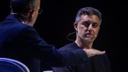 Luciano Huck durante entrevista em evento, usando microfone de lapela