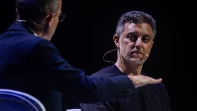 Luciano Huck durante entrevista em evento, usando microfone de lapela