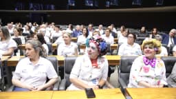 Voluntárias vestidas de palhaças, com nariz vermelho e perucas coloridas, sentadas em homenagem ao Hospital Amaral Carvalho na Câmara dos Deputados