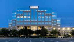 Fachada iluminada de prédio da Samsung ao entardecer, com logo da empresa no topo