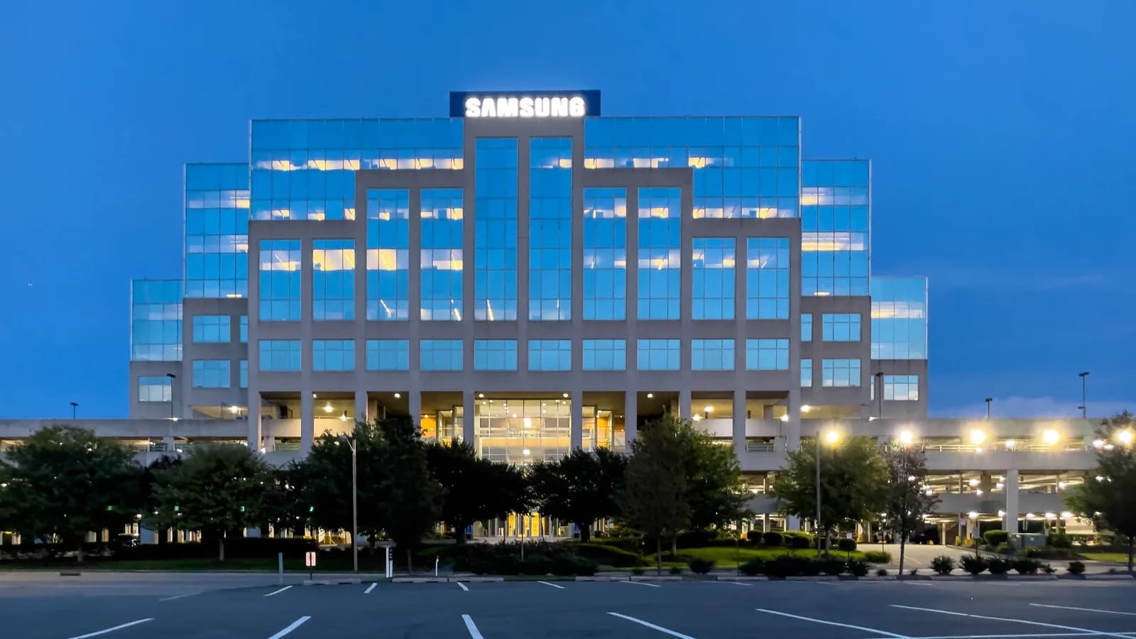 Fachada iluminada de prédio da Samsung ao entardecer, com logo da empresa no topo