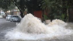 Água forma grandes poças e corre com força em rua alagada de São Paulo durante chuva
