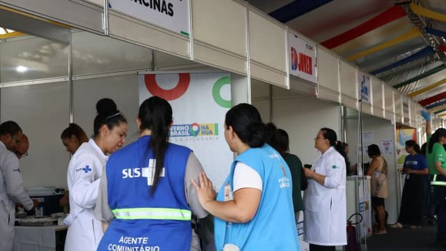 Agentes de saúde atendem público em balcão de serviços públicos ao ar livre