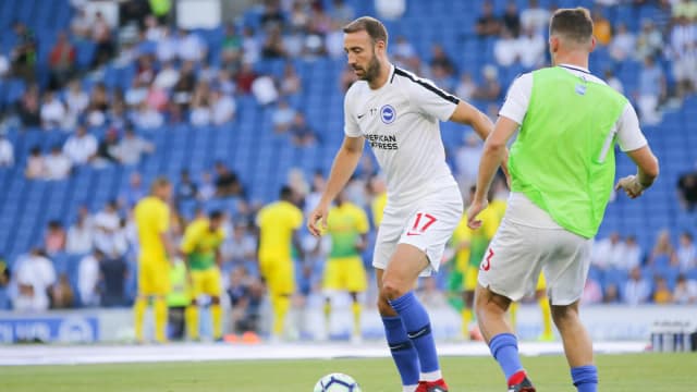 Jogador do Brighton conduz a bola durante partida, com torcida ao fundo, foto de arquivo