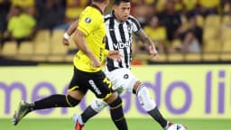 Jogador do Botafogo, de camisa listrada preta e branca, conduz a bola em jogo da Pré-Libertadores em Guayaquil