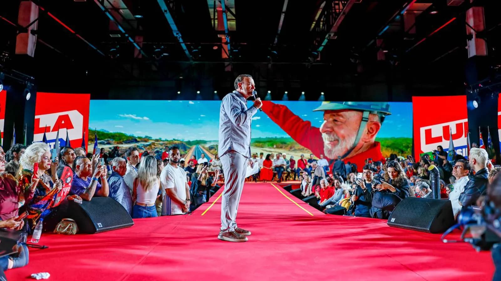 Lula discursa em palco de convenção partidária, com microfone, diante de militantes