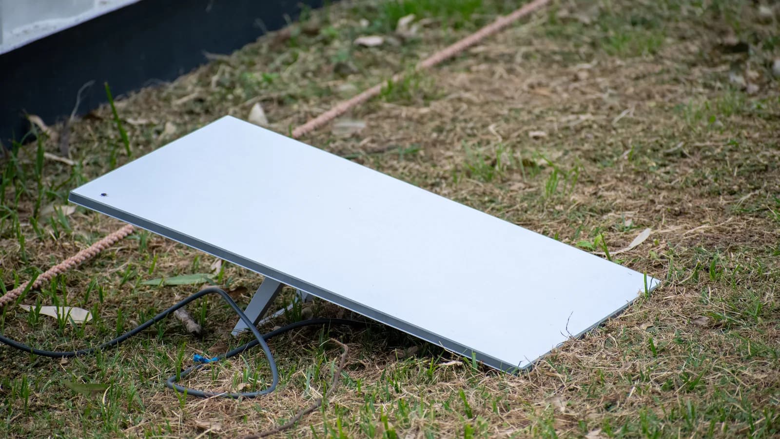 Antena retangular da Starlink instalada sobre gramado para captar sinal de internet via satélite