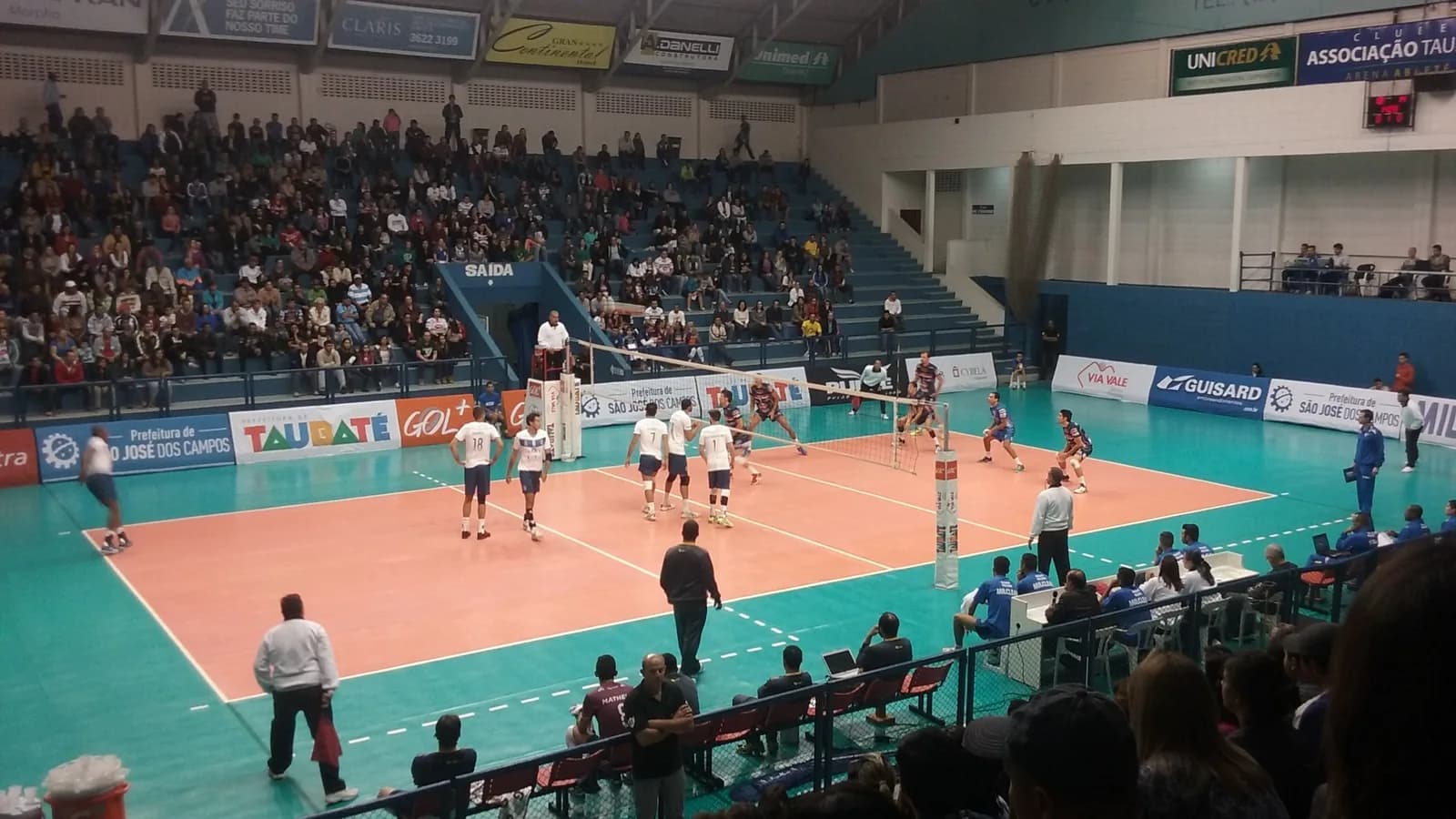 Jogadores em ação durante partida de vôlei masculino em ginásio brasileiro, foto de arquivo