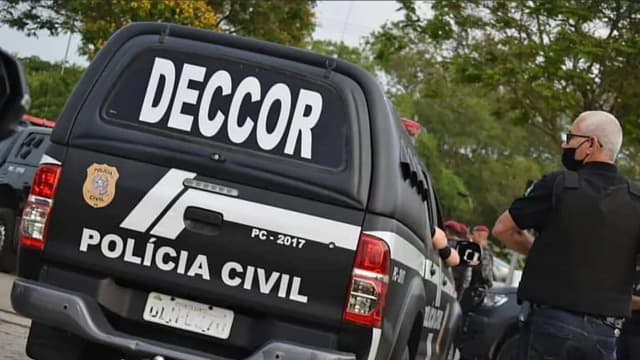 Viatura da Polícia Civil do Espírito Santo, com policial ao lado