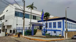 Prédio central da Universidade Federal de Itajubá, com fachada azul e branca e bandeiras hasteadas
