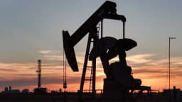 Silhueta de bomba de extração de petróleo contra o pôr do sol