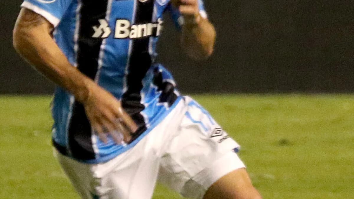 Jogador do Grêmio em ação durante partida, com o uniforme azul, preto e branco do clube