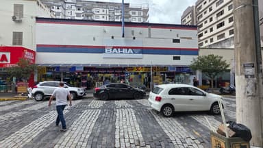 Fachada de uma loja da rede Casas Bahia em Minas Gerais, com pedestres e carros na rua