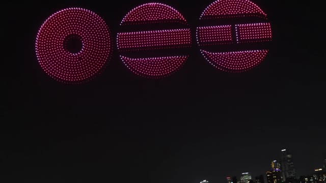 Espetáculo de drones formando figuras luminosas no céu noturno sobre uma cidade (foto ilustrativa, não é do Rock in Rio)