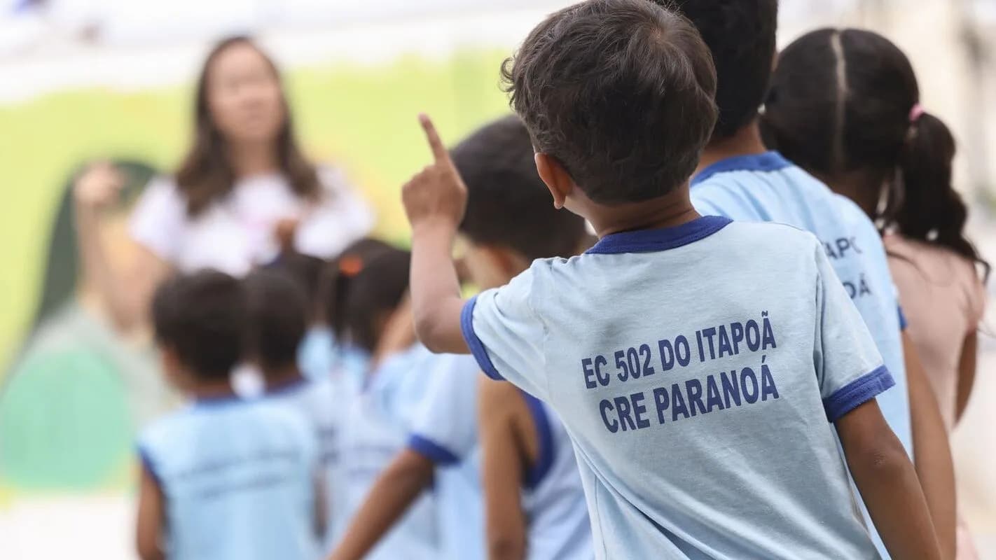 Crianças em fila acompanhadas por uma professora em ambiente escolar, foto ilustrativa