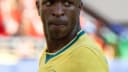 Vinícius Júnior, suado e com expressão séria, durante partida com a camisa amarela da seleção brasileira