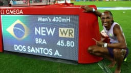 Alison dos Santos posa ao lado do painel que mostra seu recorde mundial de 45s80 nos 400m com barreiras