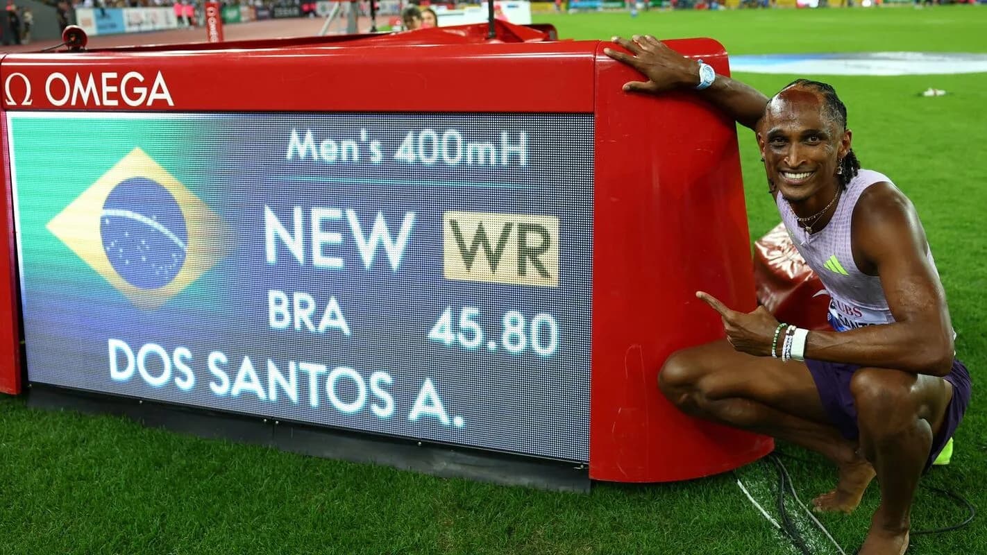 Alison dos Santos posa ao lado do painel que mostra seu recorde mundial de 45s80 nos 400m com barreiras