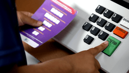 Eleitor pressiona o botão confirma em urna eletrônica com teclado em braile