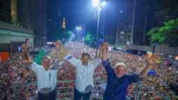 Lula ao lado de aliados políticos em ato de campanha, com multidão ao fundo (foto de arquivo)