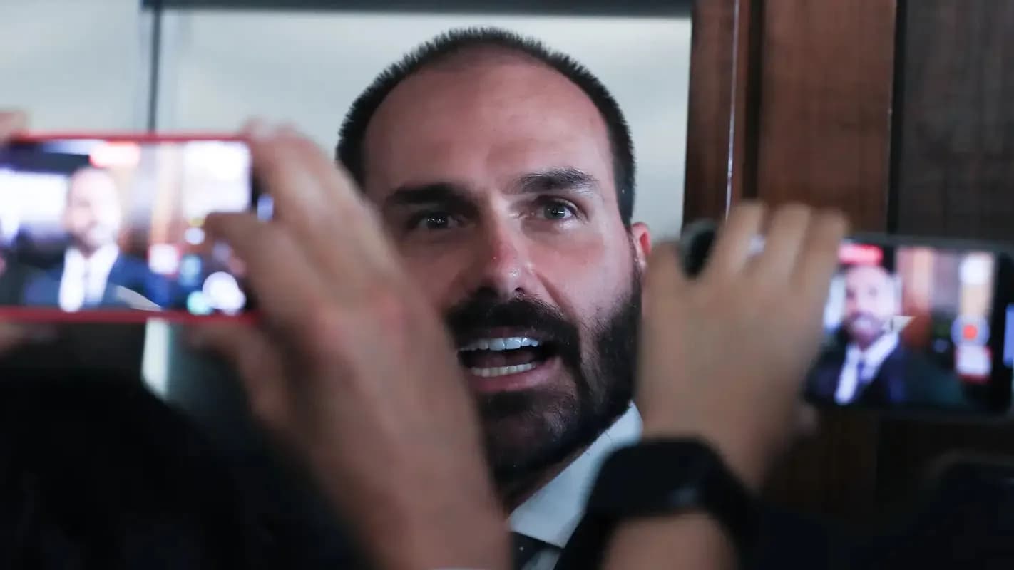 Eduardo Bolsonaro falando a repórteres, com celulares filmando em primeiro plano