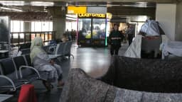 Imigrantes em área de espera de aeroporto brasileiro, com malas e colchões, foto de arquivo